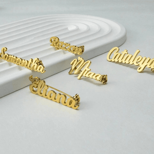 Collection of personalized name lapel pins displayed on a sleek surface featuring various names in gold