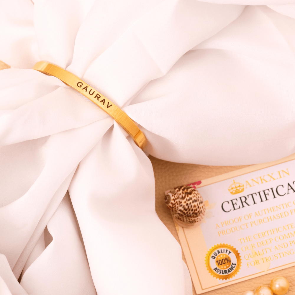 Gold Ankx.in name bracelet with personalized engravings on a soft white fabric backdrop
