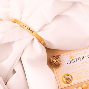 Gold-toned Ankx.in Name Bracelet engraved with GAURAV on a white fabric background with certificate