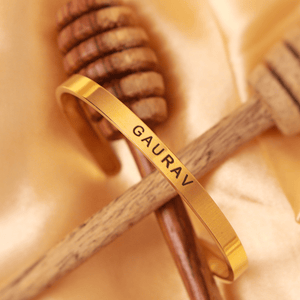 Gold-colored Name Bracelet engraved with the name Gaurav by Ankx.in on a satin background
