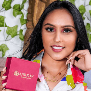 Elegant name necklace displayed by a model holding an Ankx.in gift box in a vibrant setting