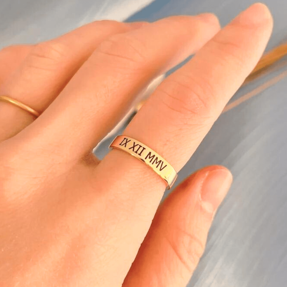 Ankx.in gold name ring with Roman numeral engraving worn on finger