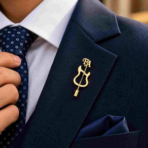 Gold guitar-shaped personalized brooch worn on a navy blue tailored suit lapel with FA initials