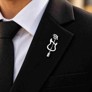 Silver guitar-shaped personalized brooch worn on a black tailored blazer with FA initials