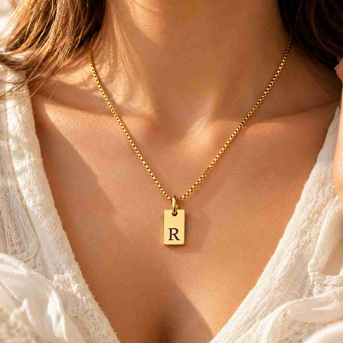Woman wearing a gold personalized R initial necklace with black engraved pendant