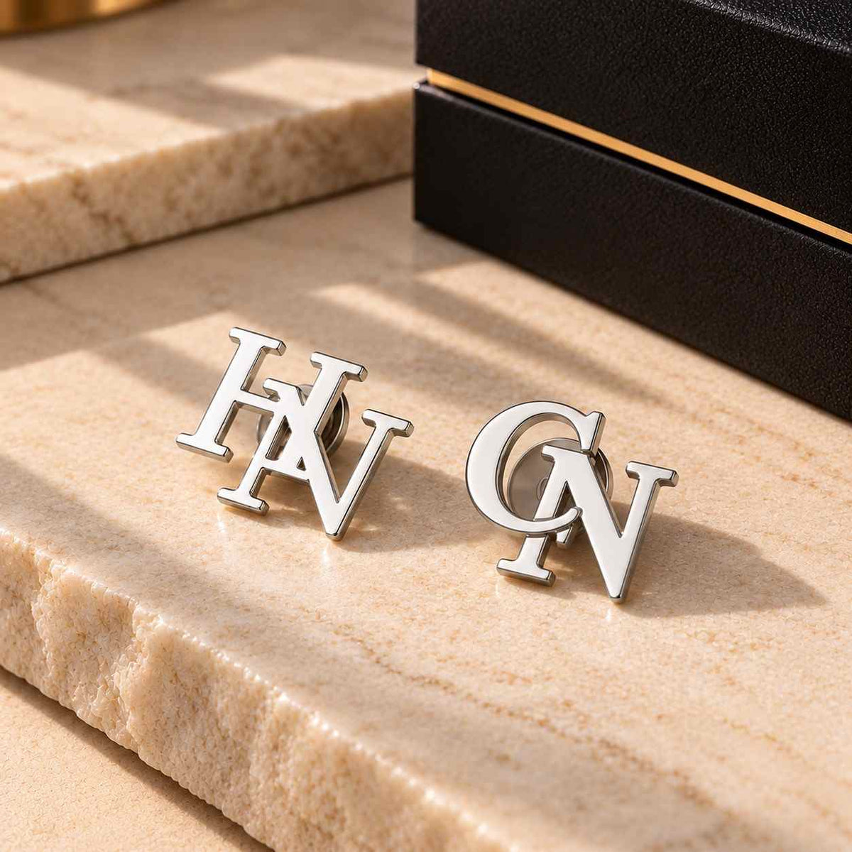 Custom Initial Lapel Pin featuring silver initials HN and CN on a marble surface for personalized style