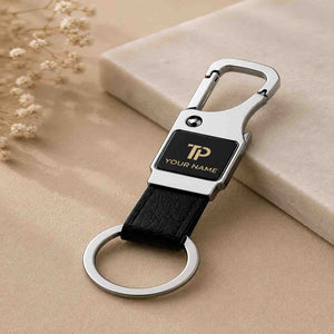Close-up of a leather keychain with carabiner clip and metal tag engraved with custom name and logo