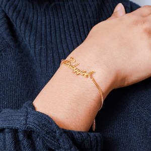 Custom name chain bracelet in gold worn on a wrist, showcasing elegant cursive lettering