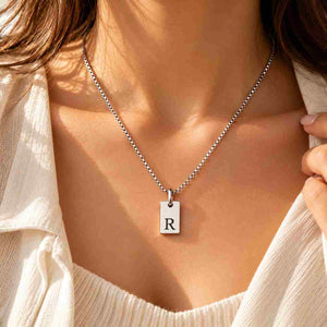 Woman wearing a silver personalized R initial necklace with black engraved pendant