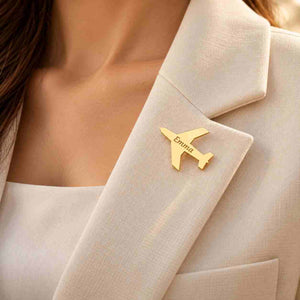 Personalized gold airplane brooch engraved with Emma worn on an elegant cream blazer