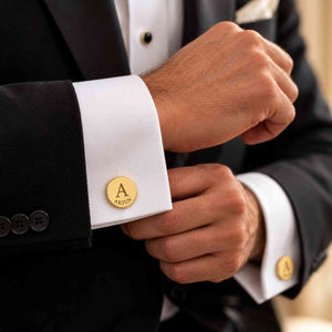 Personalized gold initial cufflink with engraved name worn on a groom's white shirt cuff