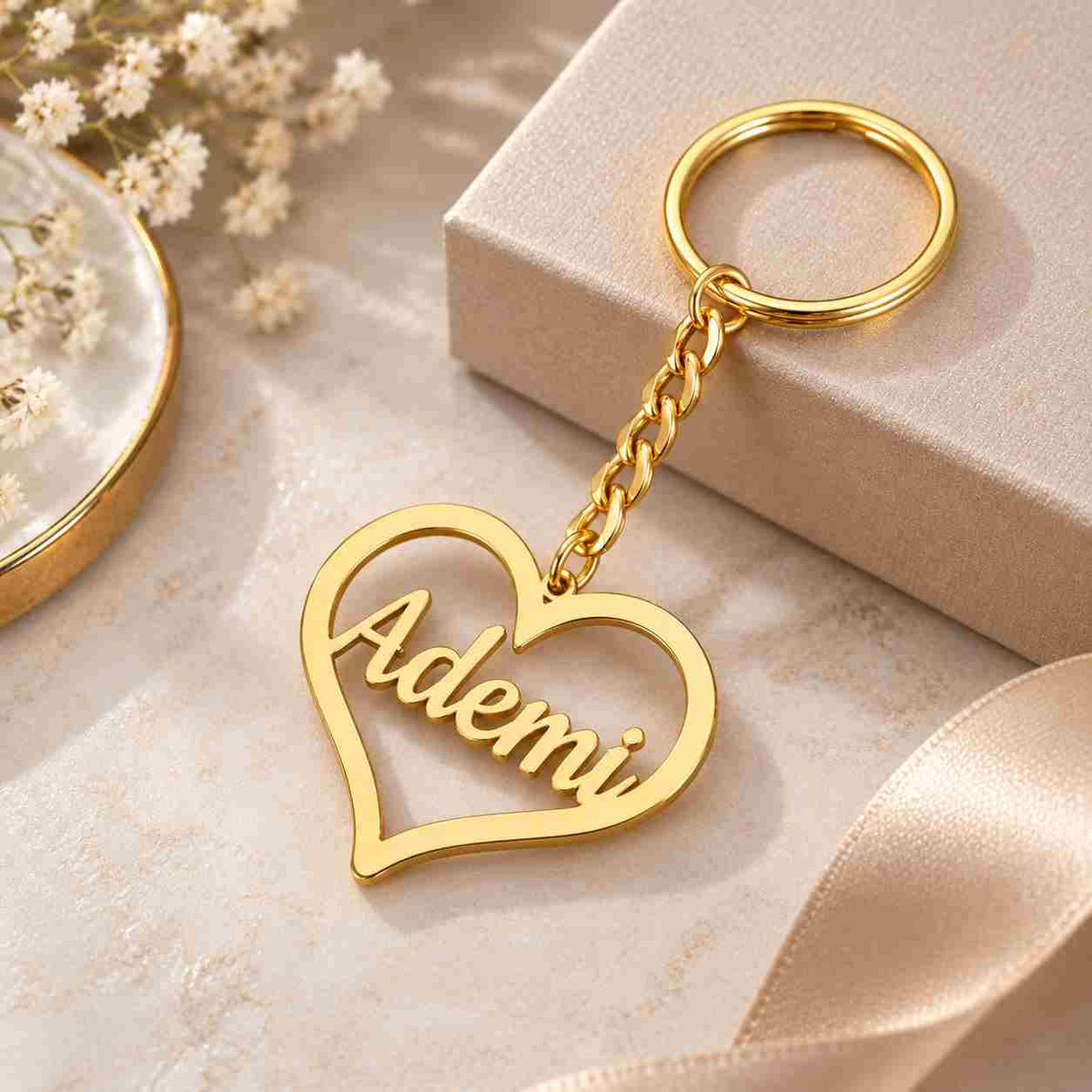Gold personalized heart keychain with the name Ademi on a soft cream background with elegant gift styling.