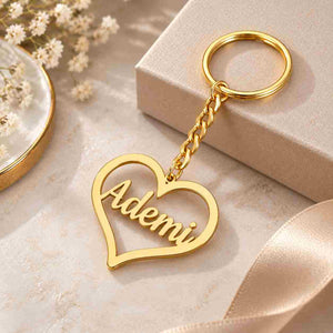 Gold personalized heart keychain with the name Ademi on a soft cream background with elegant gift styling.