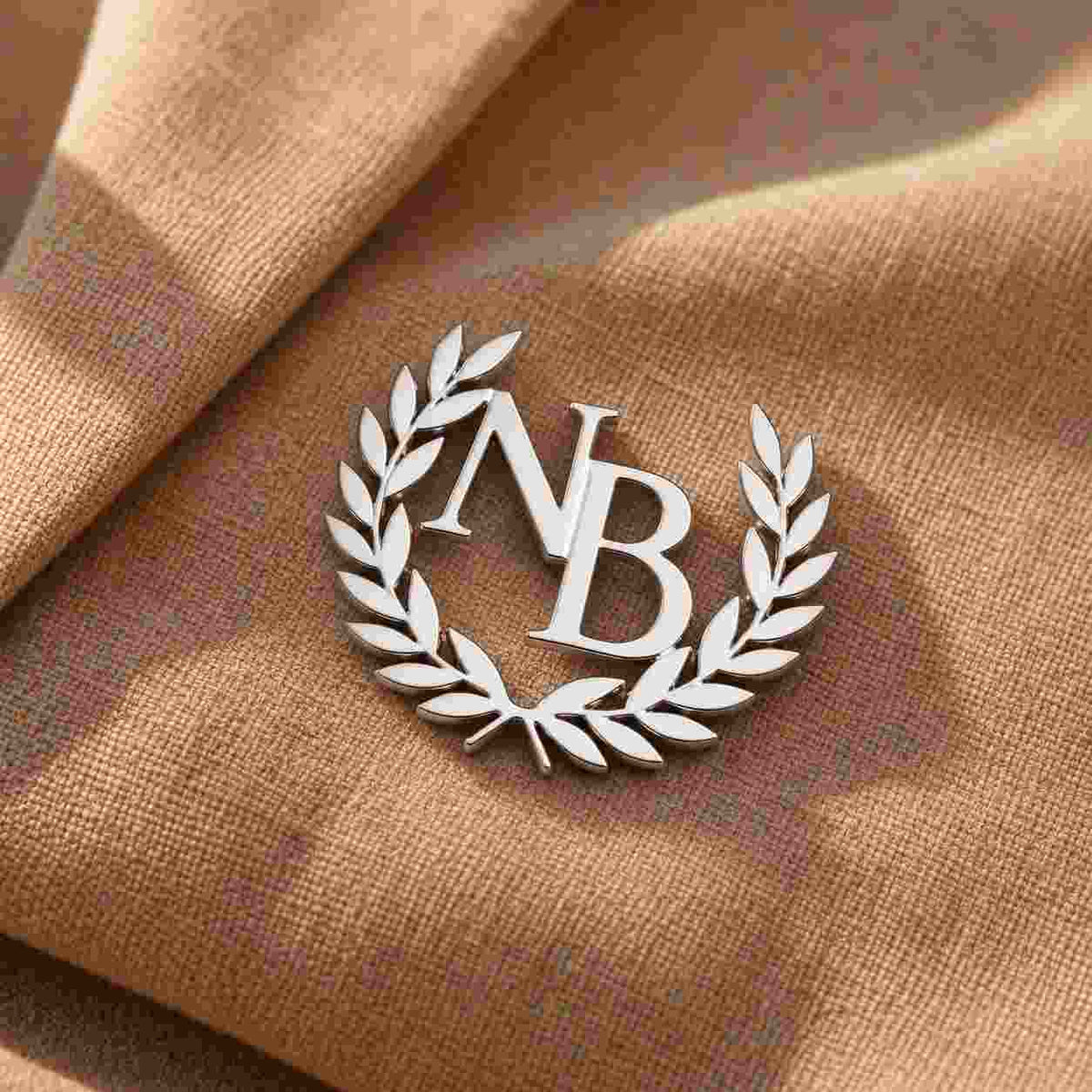 Personalized Monogram Lapel Pin with initials NB in silver on a tan fabric background