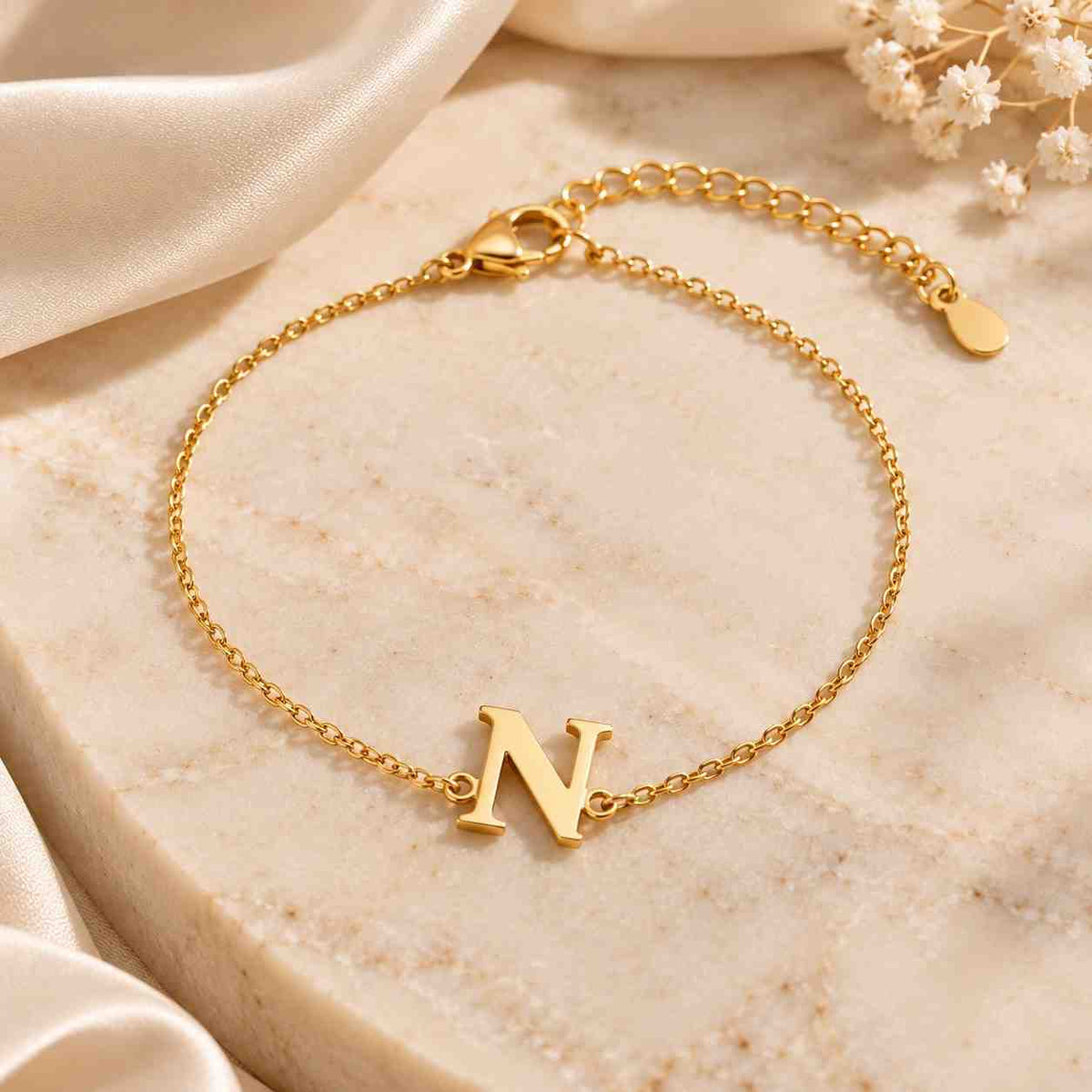 Gold N initial bracelet displayed on cream marble with delicate chain, clasp and adjustable extension