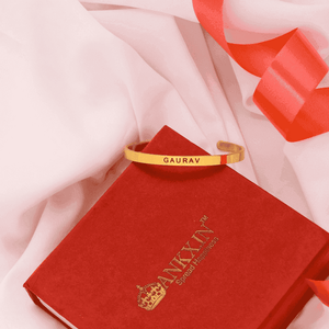Personalised name bracelet by Ankx.in displayed on a red gift box with a ribbon