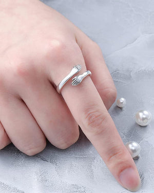Stylish silver hug ring featuring two hand designs, perfect for trendy jewelry lovers