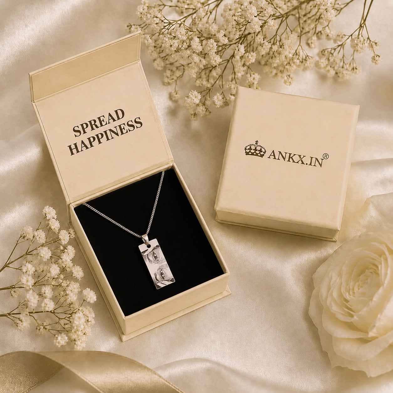 Close-up of a custom silver photo engraved necklace resting on black velvet inside an open cream-colored ANKX jewelry box.