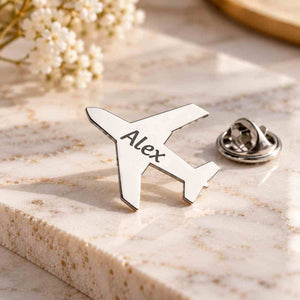 Personalized silver airplane brooch engraved with Alex displayed on a luxury marble surface