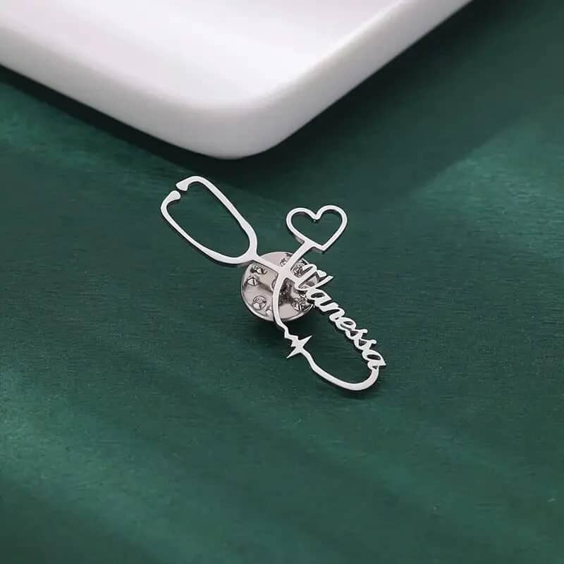 Silver stethoscope brooch with custom name and heart charm on green background